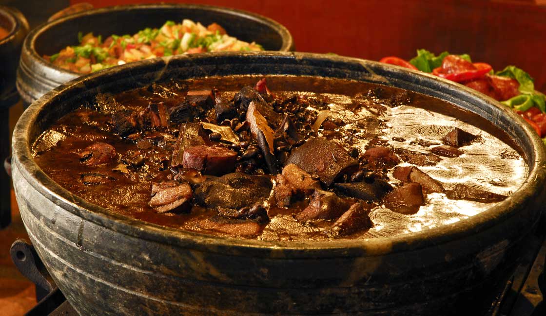 Feijoada tradicional brasileira com farofa, couve e laranja